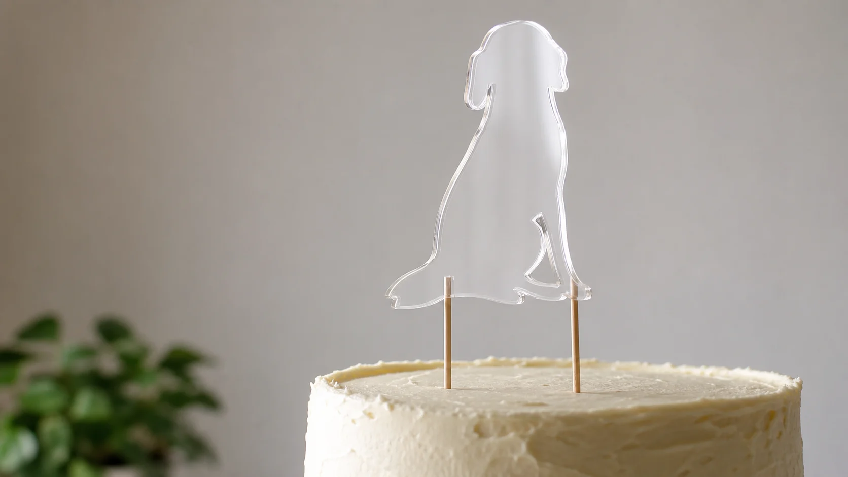 Clear acrylic cake topper standing on two skewers pushed into a buttercream cake